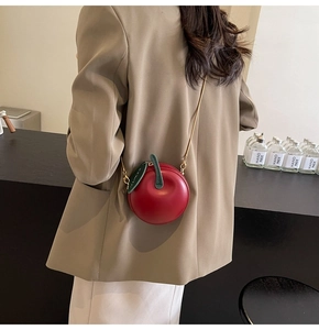 Detail view of mini red apple crossbody bag with green leaf decor and chain strap