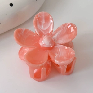 Détail macro d'une pince à cheveux fleur rose avec texture marbrée et finition lisse