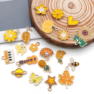 Detailed set of yellow enamel charms including flowers and leaves on a wooden base