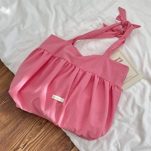 Detailed macro view of pink pleated fabric shoulder bag with soft texture and bow strap