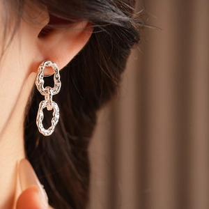 Gros plan de boucles d'oreilles argentées à trois anneaux avec texture plissée sur un modèle