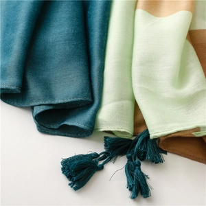 Detail showing high-quality cotton linen fabric texture and teal fringe tassels of the shawl