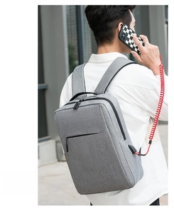 Close-up of minimalist grey laptop backpack featuring an external USB charging port in use