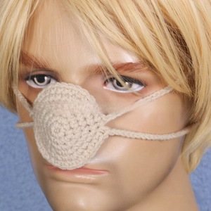 Detail of handmade crochet nose warmer in beige yarn for winter party props