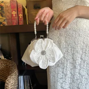 Detail of cream satin handbag with 3D floral accent and elegant pearl bead handle