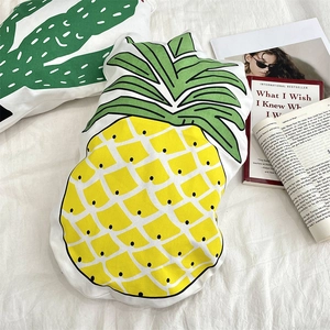 Detail of pineapple shaped decorative pillow with vibrant yellow print on white fabric