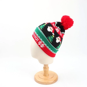 Close-up of Christmas beanie with Santa jacquard, snowflakes, and large red pom-pom