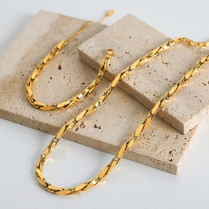 Elegant gold-plated chain necklace and bracelet set on minimalist stone display