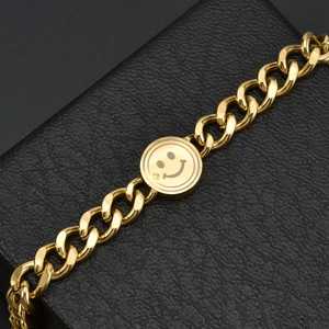 Chunky gold titanium chain bracelet with a cute smiley face pendant on a black background
