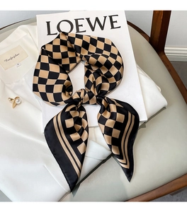 Detail of checkered silk scarf tied in a bow on a white shirt and book