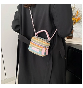 Dettaglio della mini borsa in paglia a righe colorate con manico in pelle rosa e catena