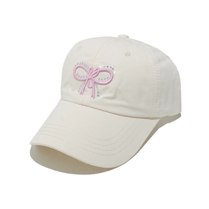 Detail of cream baseball cap featuring pink embroidered bow with sparkling rhinestones