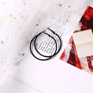 Boucles d'oreilles créoles noires mates posées sur tulle étoilé et pages de livre ancien