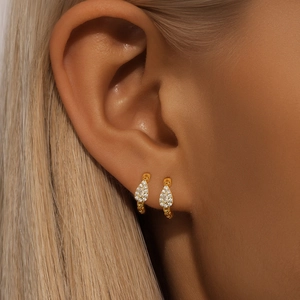 Macro shot of gold hoop earrings with sparkling teardrop-shaped pavé zircon charms