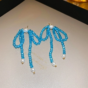 Dettaglio orecchini a fiocco in cristallo azzurro con nappe di perle bianche