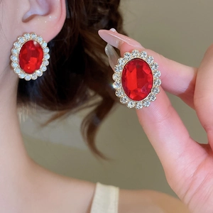 Macro view of vintage gold earrings with oval red gemstones and clear zircon halo