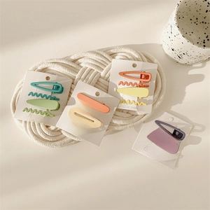 Set of 4 matte pastel hair clips in blue, orange, yellow, and lilac tones on white background