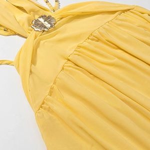 Detailed close-up of yellow mesh dress with gold flower buckle and bead strings
