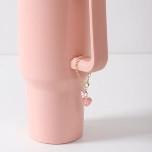 Detail of pink enamel heart charm with letter A and butterfly on cup handle