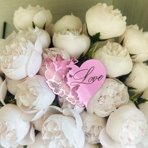 Gros plan d'un cake topper cœur en acrylique rose avec papillon et gravure Love