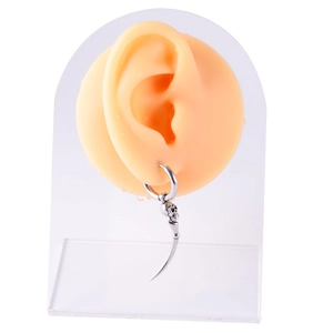 Detailed view of silver skull hoop earring with curved spike on ear model