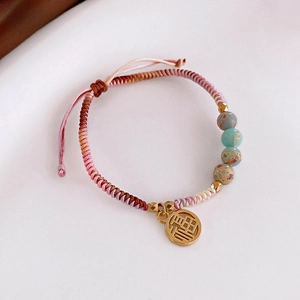 Macro shot of hand-woven gradient bracelet with natural stone beads and gold Fu pendant