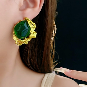 Detail of vintage gold-framed emerald green resin earrings worn on a model's ear