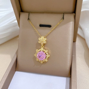 Detailed close-up of a gold flower necklace with pink zircon in a premium gift box