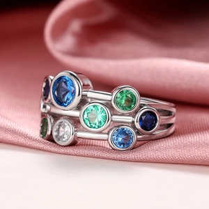 Macro shot of silver multi-layer ring with round blue, green and white gemstones on silk