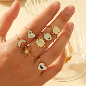 Golden 7-piece adjustable ring set featuring clover, heart and moon motifs with white enamel
