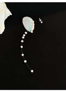 Detail of freshwater pearl tassel earrings with shell accents on a black background
