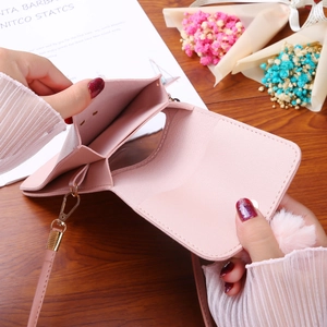 Pink crossbody phone bag with touchscreen window, card slots and plush ball charm