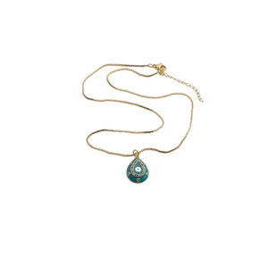 Macro view of gold evil eye necklace with turquoise teardrop pendant and zircon details