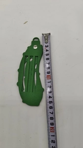Detailed view of a green wooden pickle ornament with vertical cutout design and top ring
