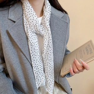Close-up of elegant white polka dot fabric scarf necklace paired with a grey wool coat