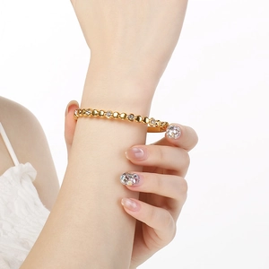 Vue détaillée d'un bracelet fin en acier titane doré avec billes et diamants incrustés