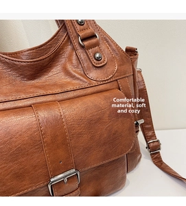 Close-up of brown vintage leather tote with decorative silver studs and buckle detail