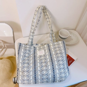 Détail du sac cabas matelassé avec motifs floraux, dentelle bleue et étiquette tissée