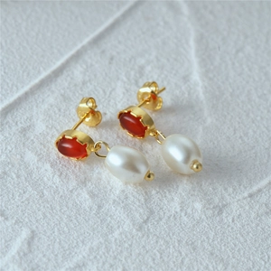 Detailed macro shot of vintage gold earrings with red agate and white teardrop pearls
