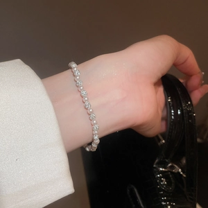 Close-up of pearl and diamond-studded bead bracelet on wrist with elegant lighting