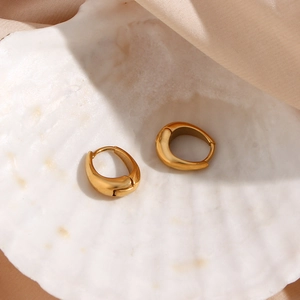 Detailed view of gold pear-shaped hoop earrings placed on a shell with pink satin fabric