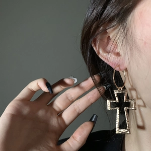 Close-up of gold cross hoop earrings with textured finish worn by a model