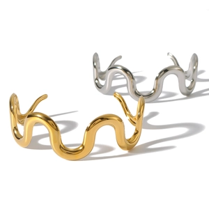 Polished 18K gold and silver wavy open cuff bracelets on a minimalist white background