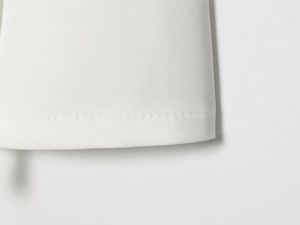 Detailed macro view showing premium white fabric texture and precision stitching on hemline
