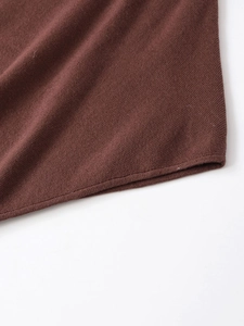Detailed macro view of the soft brown knit fabric hem with fine stitching craftsmanship