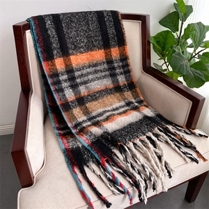 Close-up of checkered winter scarf with orange and beige patterns and fringe details