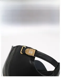 Close-up of adjustable bronze metal buckle and leather strap on a black baseball cap