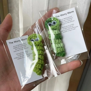Detailed view of handmade green crochet Worry Worms in transparent gift packaging