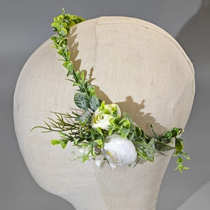 Close-up of white fabric roses and green leaves on a bridal flower headband