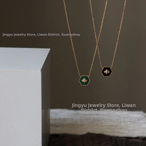 Detail of green malachite and black hexagon pendants with gold bee on bead chain